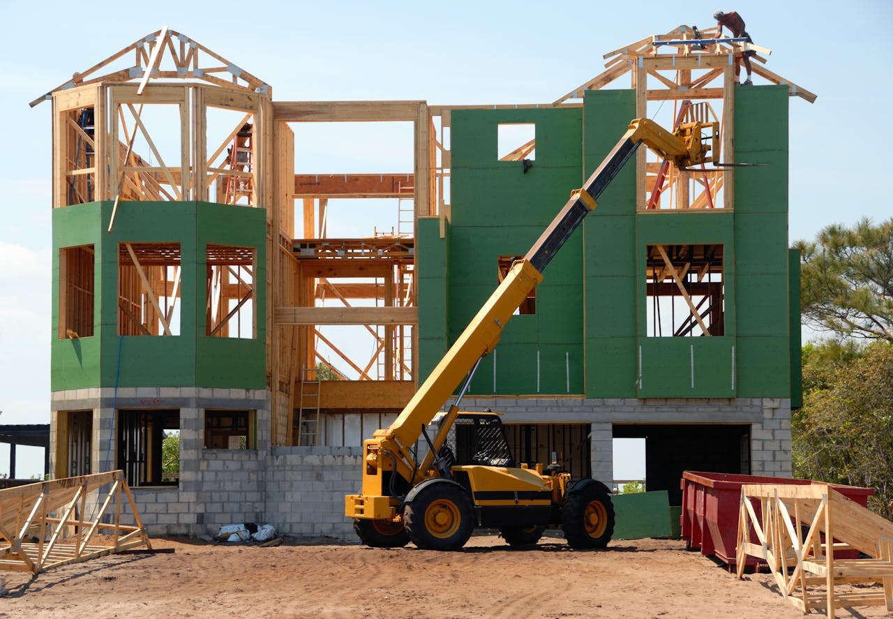 services-01 A multi-story wooden house under construction using a crane on a sunny day.
