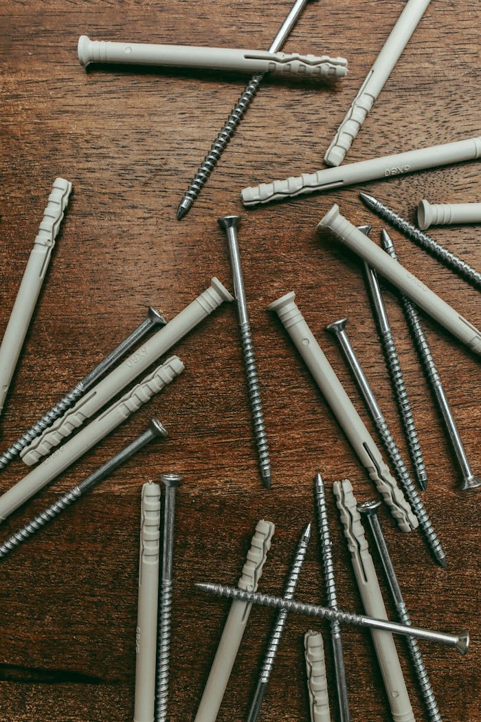 Scattered screws and nylon anchors on a wooden table, ideal for hardware and construction themes.
